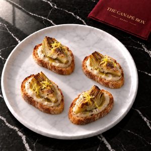 Four Artichoke & White Bean Crostini canapés on a marble plate