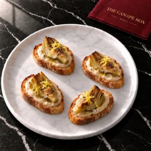 Four Artichoke & White Bean Crostini canapés on a marble plate
