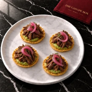 Four Short Rib Tostada canapés on a marble plate