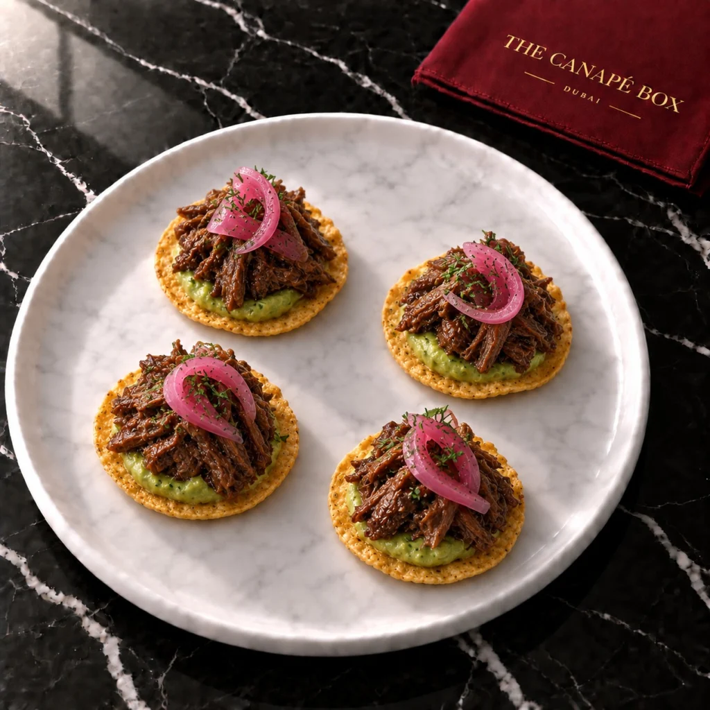 Four Short Rib Tostada canapés on a marble plate