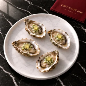 Four portions of Oyster Pearl with Cucumber Mignonette on a white marble plate