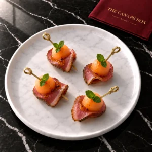 Four portions of Smoked Duck & Cantaloupe Skewer on a white marble plate