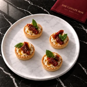 Four portions of Cashew Cheese & Sun-dried Tomato Tartlet on a white marble plate