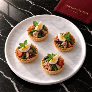Four portions of Tuna Niçoise Tartlet on a white marble plate