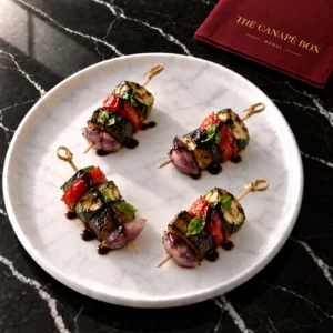 Four portions of Roasted Vegetable Antipasti Skewer on a white marble plate