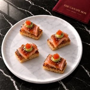 Four portions of Salmon Tataki on Crispy Rice on a white marble plate