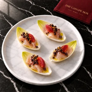 Four portions of Kingfish & Citrus on Endive on a white marble plate