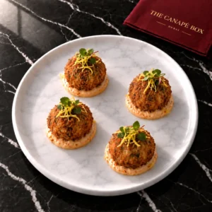 Four portions of Lamb Harissa Arancini on a white marble plate