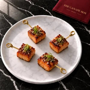 Four portions of Miso Glazed Salmon Skewer on a white marble plate