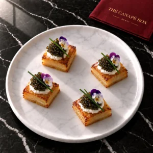 Four portions of Oscietra-Style Caviar Potato Pavé on a white marble plate