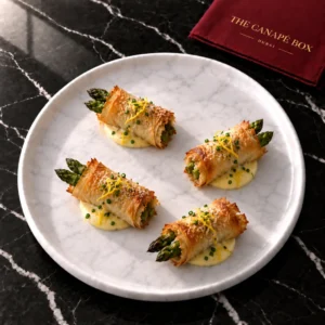 Four portions of Asparagus & Parmesan Filo Roll on a white marble plate
