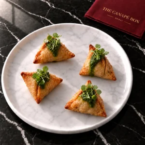 Four portions of Vegetable Samosa with Mint Chutney on a white marble plate