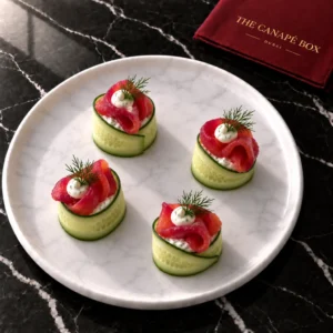 Four portions of Beetroot-Cured Salmon Cucumber Roll on a white marble plate