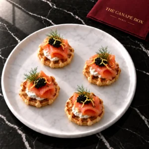 Four portions of Smoked Salmon & Caviar Waffle on a white marble plate