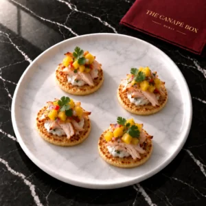 Four portions of Smoked Chicken & Mango Corn Blini on a white marble plate