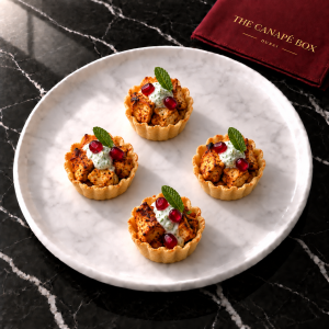 Four portions of Chicken Tikka Tartlet on a white marble plate