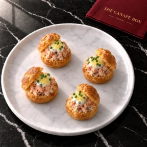 Four portions of Salmon Rillettes Choux on a white marble plate