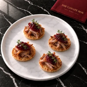 Four portions of Duck Confit & Sour Cherry Crisp on a white marble plate