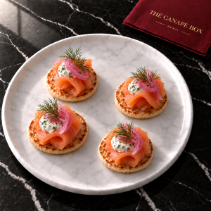 Four portions of Smoked Salmon Blini on a white marble plate