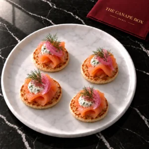 Four portions of Smoked Salmon Blini on a white marble plate