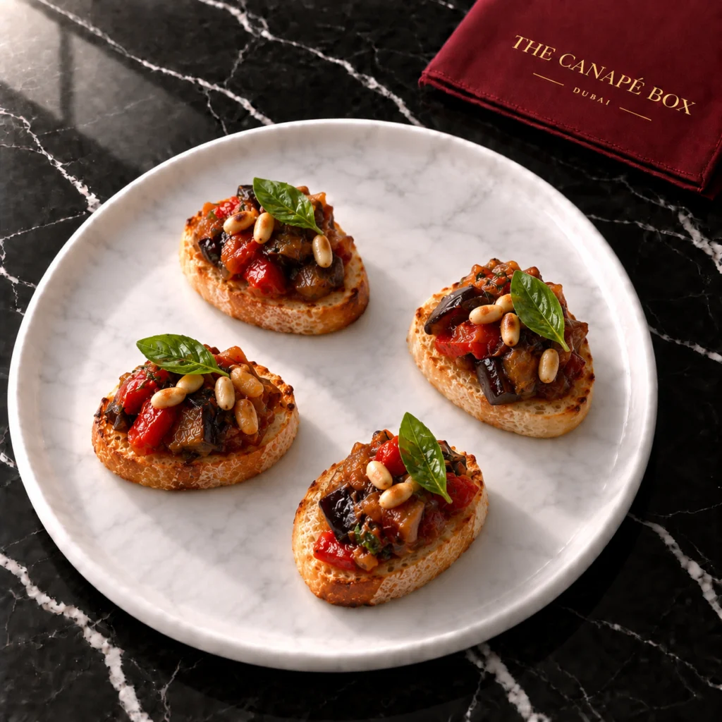 Four portions of Caponata Crostini with Pine Nuts on a white marble plate