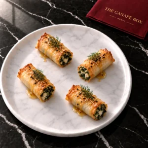 Four portions of Spinach & Feta Filo Cigar on a white marble plate