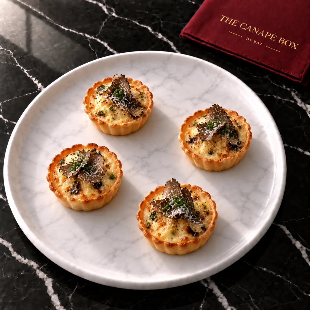 Four portions of Truffle & Parmesan Custard Tartlet on a white marble plate