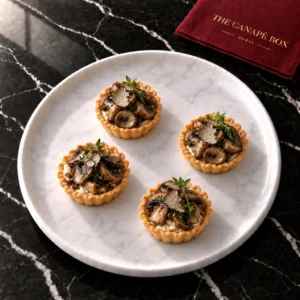 Four portions of Wild Mushroom Tartlet on a white marble plate