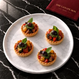 Four portions of Mini Ratatouille Tartlet on a white marble plate