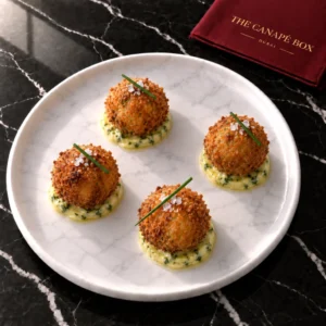 Four portions of Chicken Kyiv Bonbon on a white marble plate