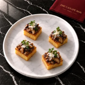 Four portions of Parmesan Polenta Cube with Mushroom Ragout on a white marble plate