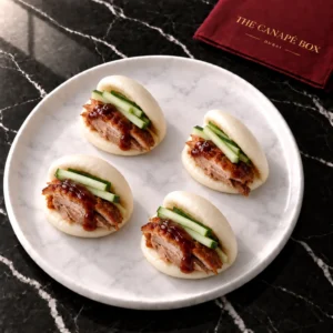 Four portions of Duck & Plum Bao Bite on a white marble plate