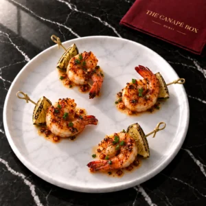 Four portions of Chilli Garlic Prawn Skewer on a white marble plate