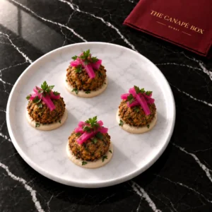 Four portions of Falafel Bite with Tahini & Pickled Turnip on a white marble plate