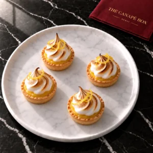 Four portions of Lemon Meringue Tartlet on a white marble plate