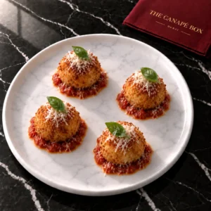 Four portions of Mozzarella Arancini with Marinara on a white marble plate