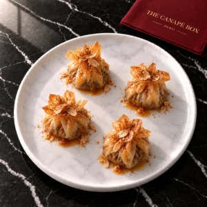 Four portions of Lamb & Apricot Pastilla Bite on a white marble plate