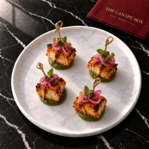Four portions of Tandoori Fish Tikka Bite on a white marble plate