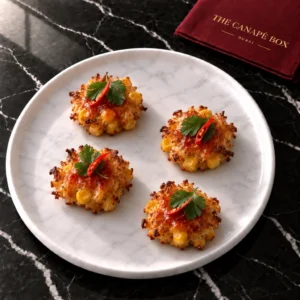 Four portions of Coconut & Corn Fritter with Sweet Chilli on a white marble plate
