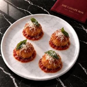 Four portions of Chicken Parmigiana Arancini on a white marble plate