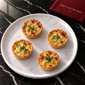 Four portions of Leek & Gruyère Mini Quiche on a white marble plate