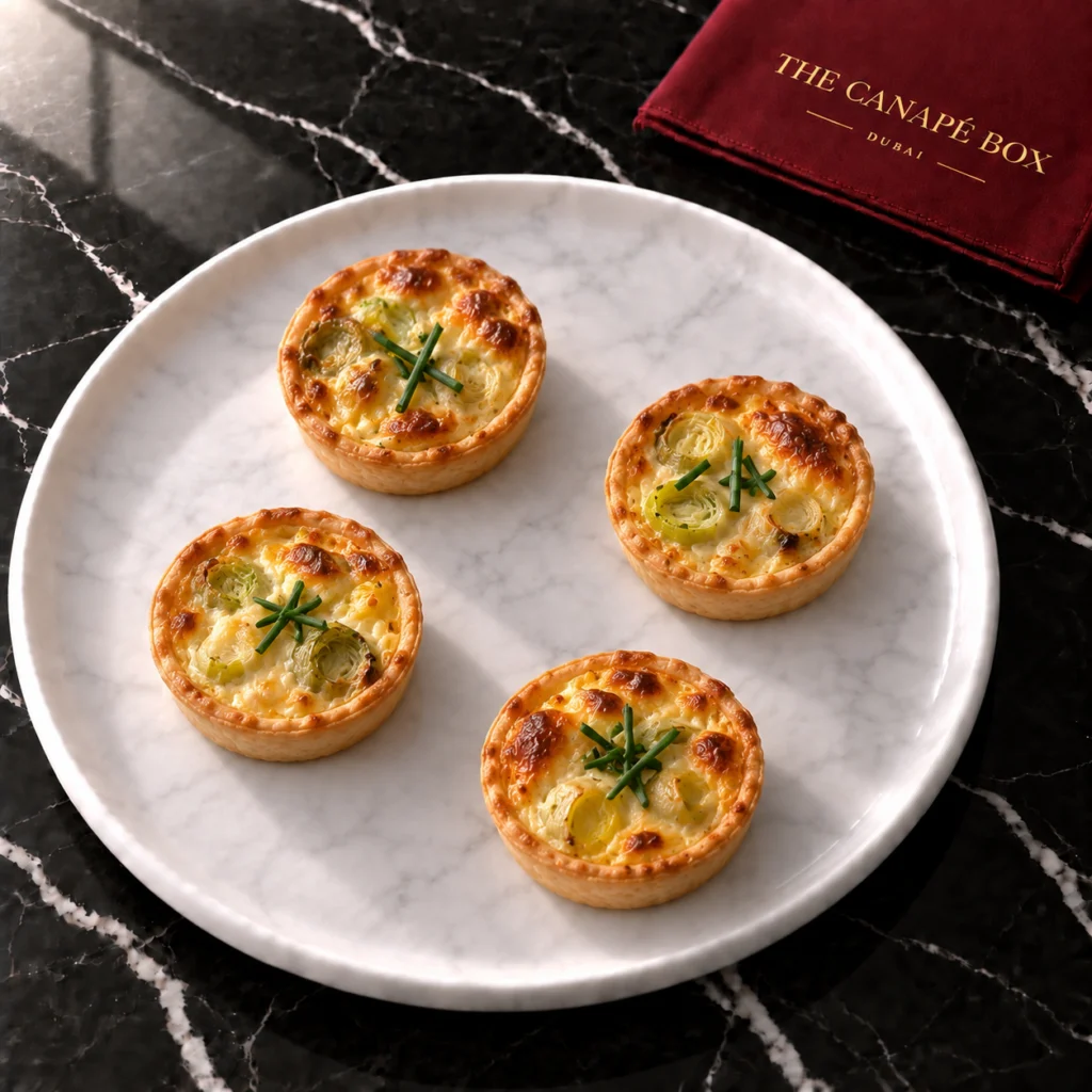 Four portions of Leek & Gruyère Mini Quiche on a white marble plate