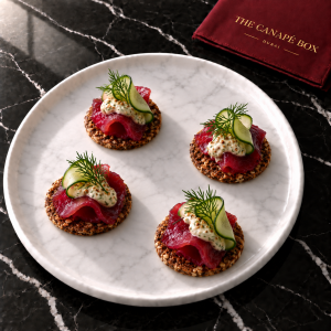 Four portions of Beetroot Gravlax on Rye on a white marble plate