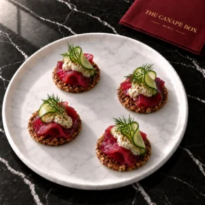 Four portions of Beetroot Gravlax on Rye on a white marble plate