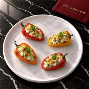 Four portions of Stuffed Baby Peppers with Herbed Ricotta on a white marble plate