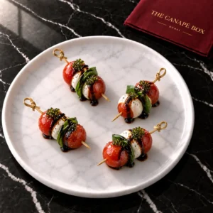 Four portions of Caprese Skewer with Basil Pearl on a white marble plate