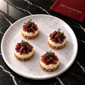Four portions of Goat Cheese Cheesecake Bite with Red Onion Marmalade on a white marble plate