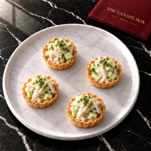 Four portions of Crab & Green Apple Tartlet on a white marble plate